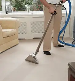 Professional carpet cleaner using a hot-water extraction wand and hose machine in a living room in San Jose, CA.