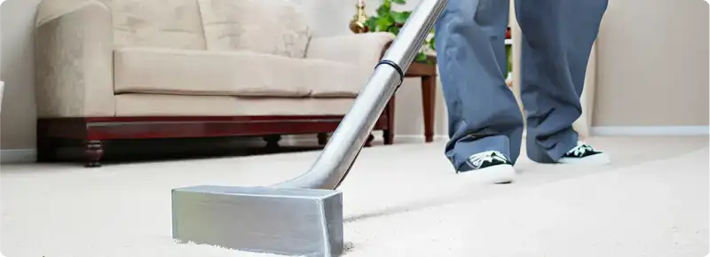 Carpet cleaning technician using a hot-water extraction wand on a light-colored carpet in a living room, San Jose, CA.
